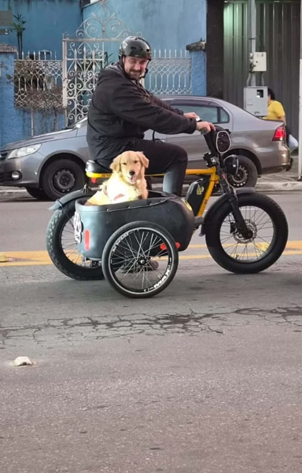 Cachorro no sidecar Sidedog, ao lado do dono na bicicleta elétrica, passeando pela rua